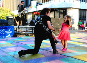 Musician Willie Nile plays guitar to a young girl at the Max & Emily's Summer Concert Series in Downtown Mt. Pleasant, Michigan in 2019.