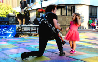 Musician Willie Nile plays guitar to a young girl at the Max & Emily's Summer Concert Series in Downtown Mt. Pleasant, Michigan in 2019.