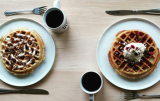 Two of Ponder Coffee Company's famous waffles, one with fruit and the other with pecans and a cup of in-house roasted coffee in Mt. Pleasant, Michigan.