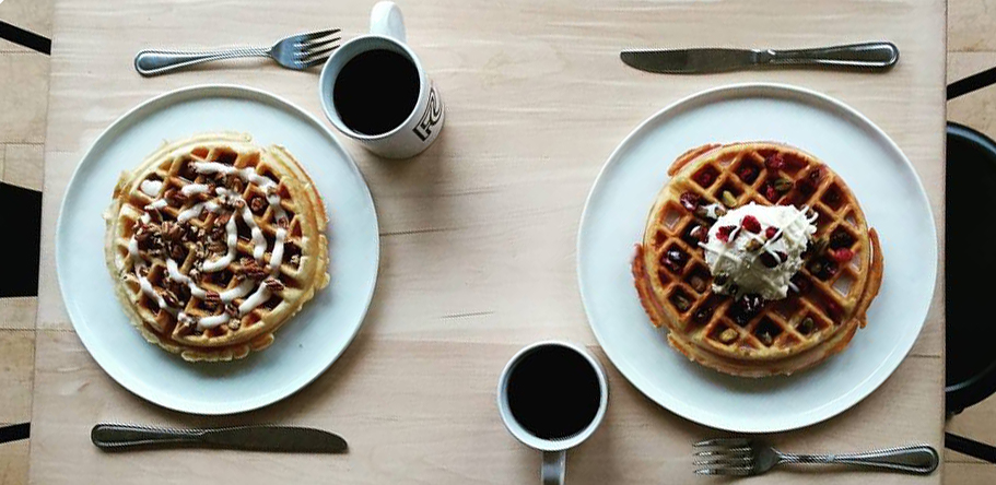 Two of Ponder Coffee Company's famous waffles, one with fruit and the other with pecans and a cup of in-house roasted coffee in Mt. Pleasant, Michigan.