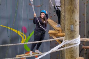 Woman on ropes course at CMU A-wall.