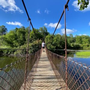 A person walking across the suspension bridge at Deerfield Nature Park.