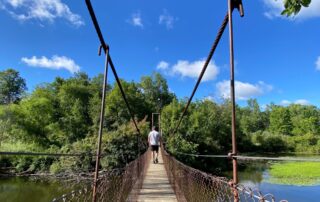 A man crossing the suspension bridge at Deerfield Nature Park.