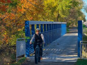 Tourist riding bicycle across blue bridge in fall